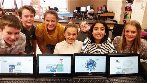 Students in front of computers with images fo earth day 