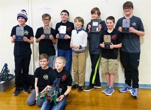 Students holding robotics trophies 