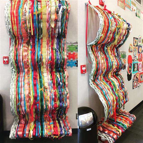 This is an image of a 3D collaborative weaving project created using recycled fencing and ribbon.